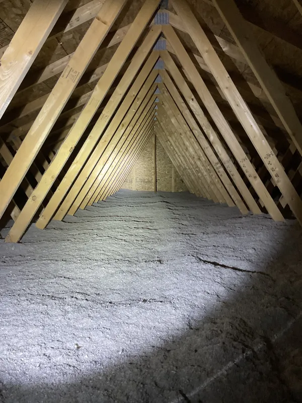Attic with blown-in cellulose insulation and exposed roof framing inspected near Madison, WI