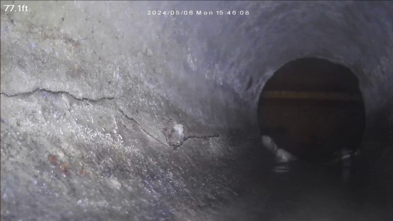 Sewer scope camera view inside a sewer line showing a crack in transite pipe