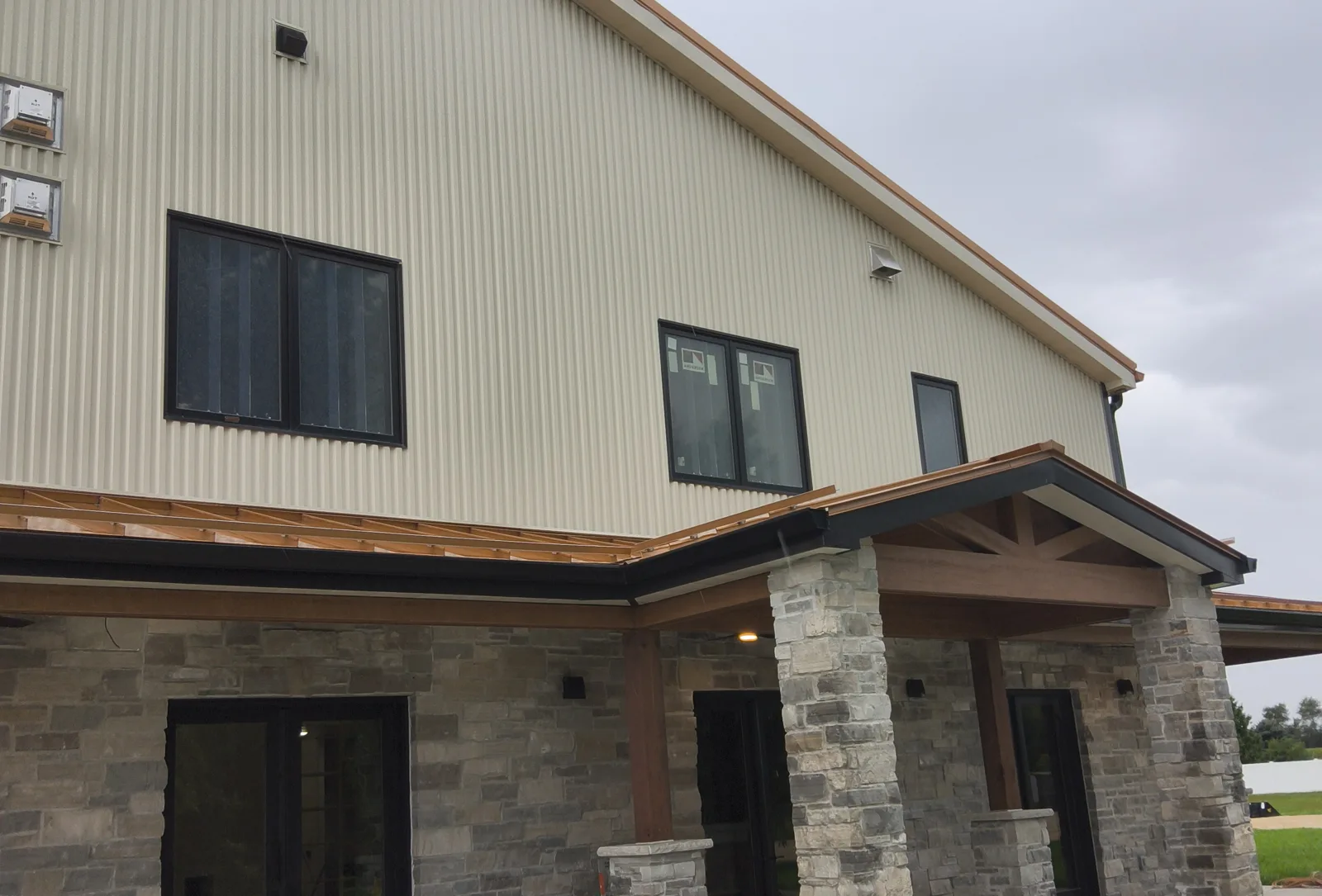 Barndominium porch with metal roof, timber trusses and stone columns in Rock County, WI