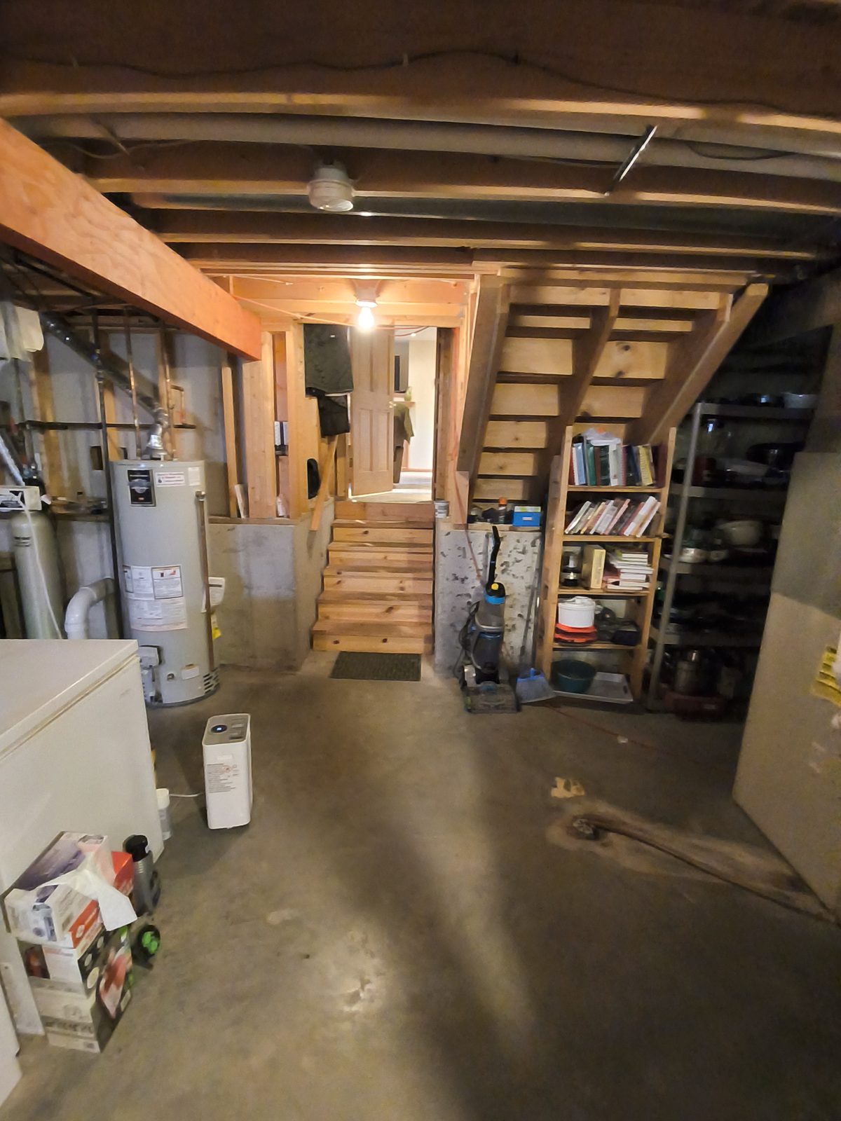 Unfinished basement mechanical area with a water heater and stairs checked during an inspection