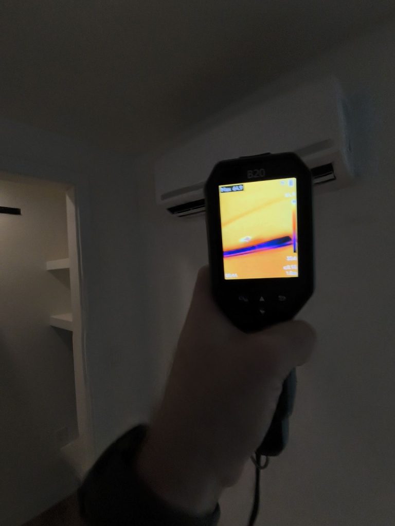 Home inspector using a thermal imaging camera to check a wall for hidden moisture in a Madison, WI home